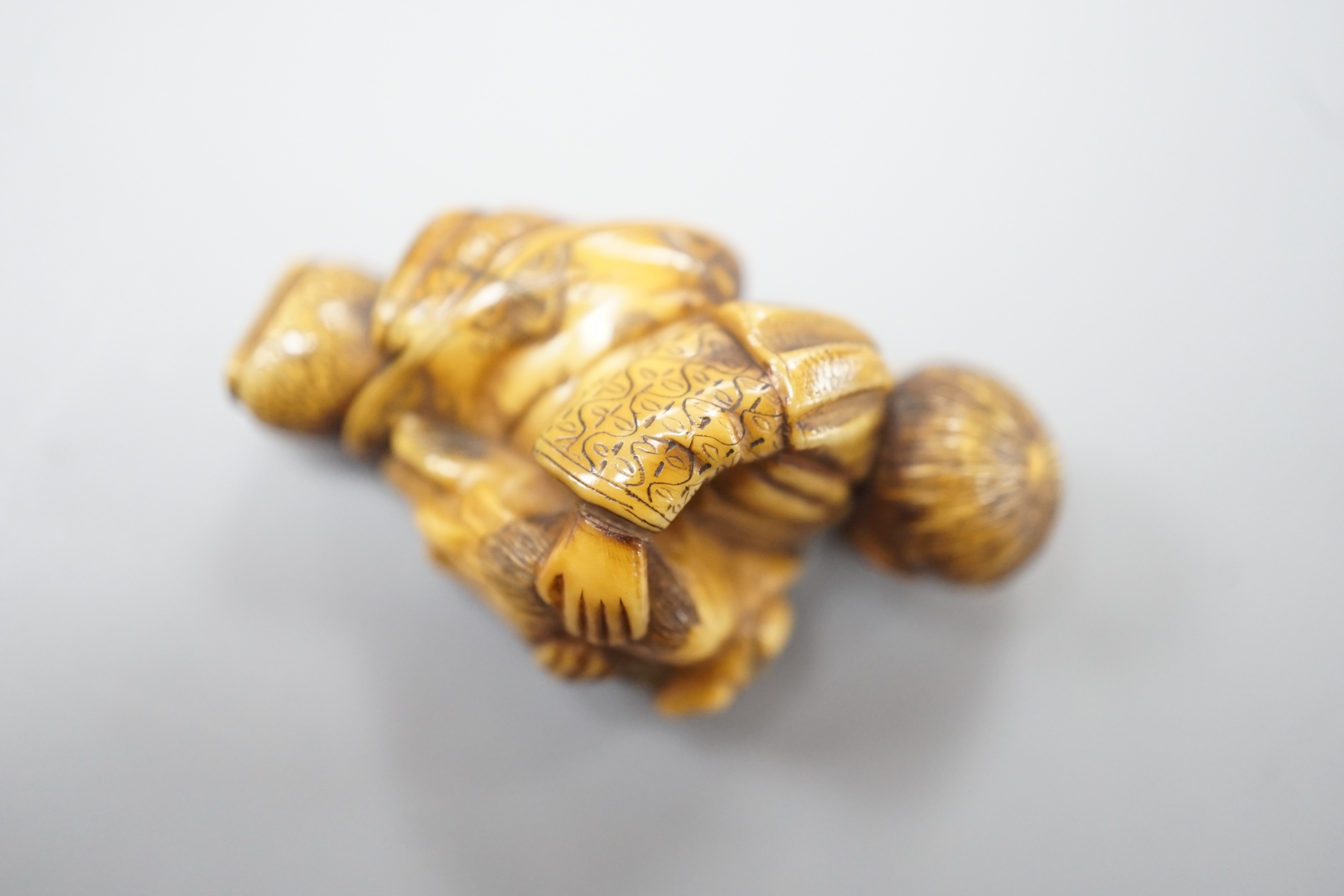 A Japanese ivory netsuke of a dog piggybacking a boy, Meiji period, 3.9cm